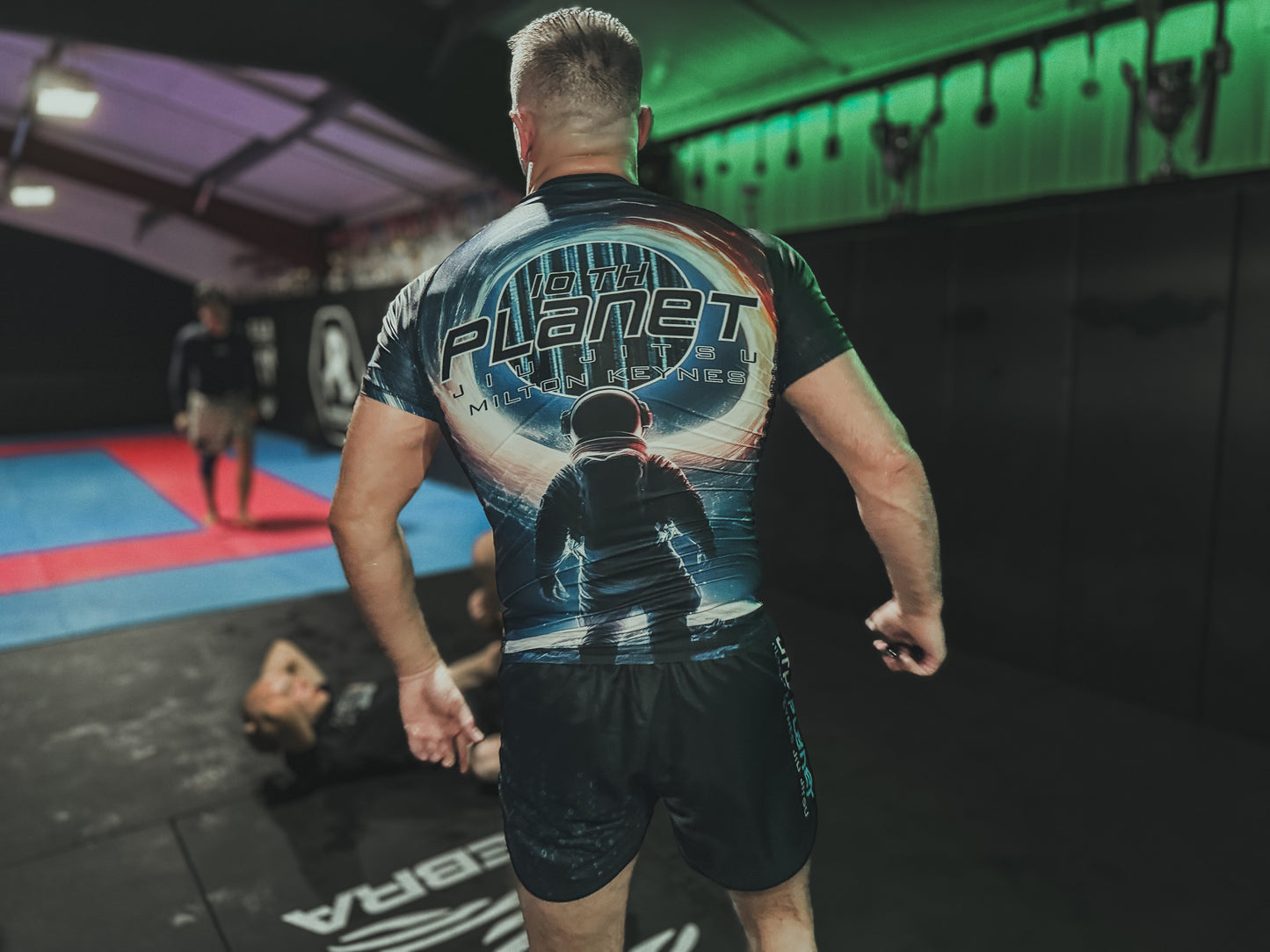 Person wearing a '10th Planet' branded rash guard in a gym setting