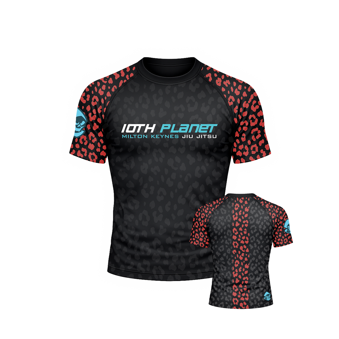 A black belt short-sleeve athletic rash guard with a subtle tonal leopard pattern, red leopard print shoulder and sleeve panels, and a blue and white '10TH PLANET' logo on the chest. A smaller inset view shows the back of the shirt with a red leopard print center panel and side sleeves.